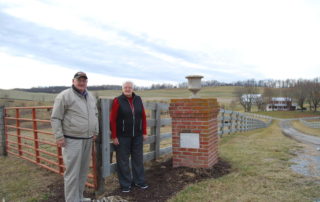 Don and Sue Hanger by the entrance gate to Berry-Moore Farm