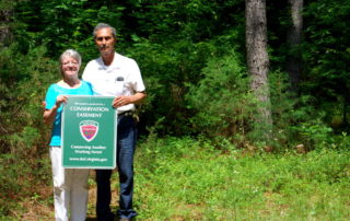 Clay and Linda Jones standing in front of words holding sign.